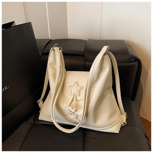 Detail view of cream white leather tote bag with star patch and drawstring closure