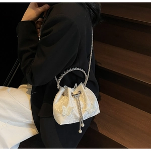 Detail of white drawstring bucket bag with butterfly embroidery and pearl charms