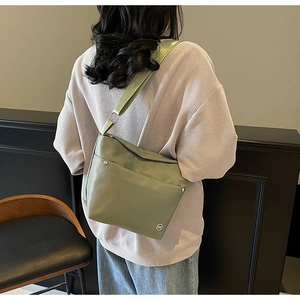 Vue détaillée du sac à bandoulière en nylon vert clair porté par un mannequin