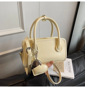 Detail of a creamy vintage square handbag with leather heart charm and silver chain handle