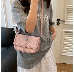 Close-up of pink crossbody bag with diagonal weave texture and vertical metal clasp