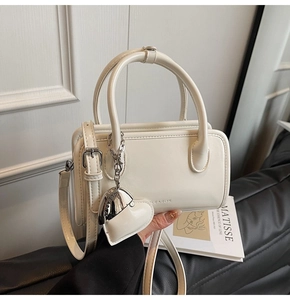 Detail shot of mini white faux leather handbag with silver heart pendant and strap