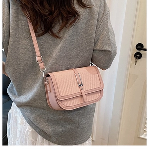 Pink crossbody bag with woven texture flap and silver buckle worn by a model