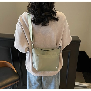 Sac seau en nylon vert olive avec large bandoulière porté par un mannequin femme