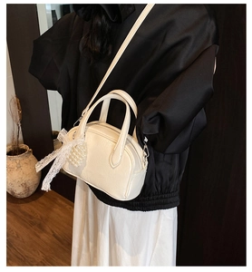 Détail du mini sac blanc avec breloque cœur perlé et nœud délicat en dentelle