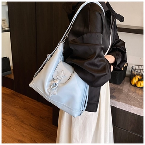 Light blue faux leather tote bag with star charms worn by a model in a modern interior