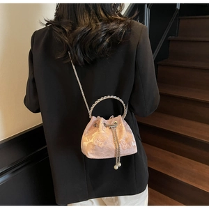 Detail of pink satin bucket bag with butterfly jacquard and round metal handle