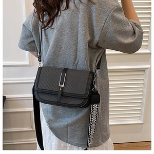 Detail of black woven shoulder bag with silver buckle and two interchangeable straps
