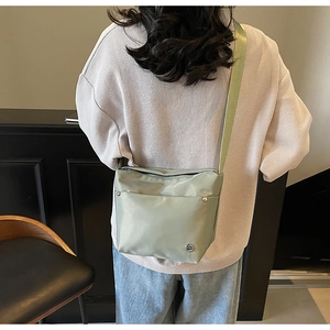 Gros plan sur sac seau en nylon vert clair avec poches zippées et rivets métalliques