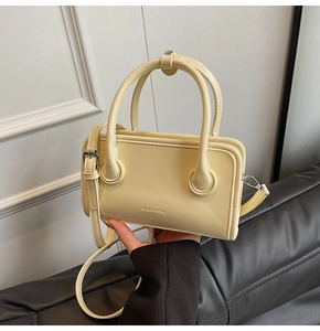 Detail of the CLEAROK cream leather handbag showing hand-held carry and embossed logo