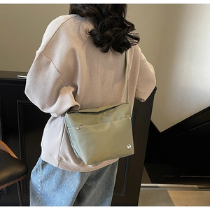 Détail du sac bandoulière en nylon vert avec sangle réglable porté par un mannequin