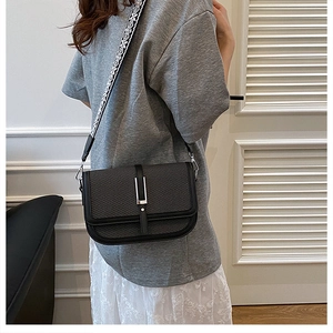 Detail of black textured crossbody bag featuring wide geometric jacquard strap and silver buckle