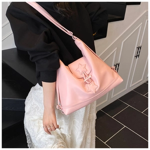 Detailed view of pink leather shoulder bag with star patches and drawstring closure