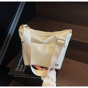 Détail du sac seau oxford blanc crème montrant le tissu nylon et la large bandoulière