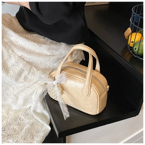 Détail d'un sac bowling en cuir PU beige avec un nœud en dentelle et pendentif perle