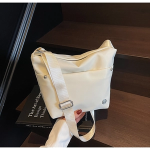 Détail du sac seau minimaliste en nylon ivoire avec clous en métal argenté et logo