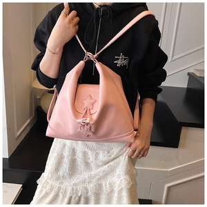 Detail of pink PU leather backpack with star charms shown in a casual lifestyle setting