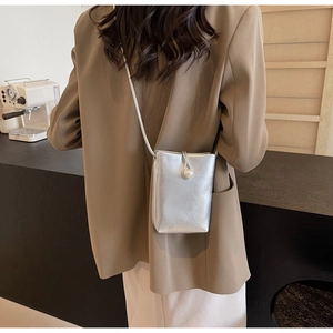 Detail showing a silver mini phone bag with an elegant oversized pearl buckle closure