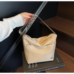 Gros plan détaillé du sac à bandoulière beige avec rivets en métal et logo de marque
