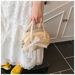 Détail du sac polochon crème avec texture vintage, nœud en dentelle et perles