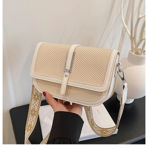 Detail of straw crossbody bag with white leather trim and geometric pattern strap