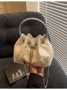 Elegant cream drawstring bucket bag with floral patterns and a rhinestone ring handle
