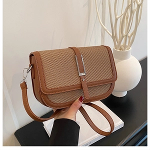 Detailed view of vintage woven crossbody bag with brown leather trim and silver metal buckle