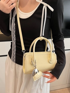 Minimalist yellow leather crossbody bag with dual handles and heart pendant charm
