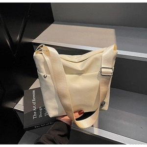 Détail du sac bandoulière en nylon crème avec sangle large et boucles en métal argenté