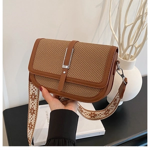 Detail of vintage square bag showing woven fabric, brown leather trim and jacquard strap
