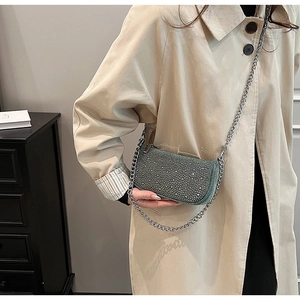 Detail of teal sequin crossbody bag with thick silver chain worn with a khaki trench coat
