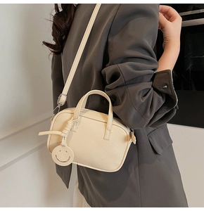 Close-up of cream crossbody phone bag with lychee texture and round smiley charm