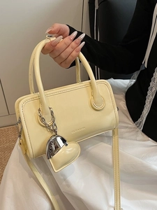 Cream yellow square Boston handbag with top handle and heart charm in a soft modern style