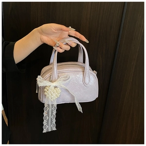 Détail du sac Boston en cuir verni lavande avec cœur perlé et nœud en dentelle