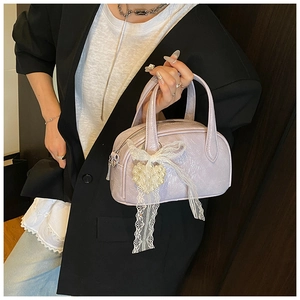 Détail du sac à main lilas plissé avec nœud en dentelle et pendentif perle cœur