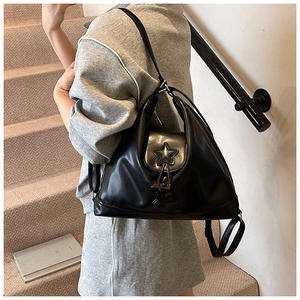 Detail shot of black leather shoulder bag featuring star emblem on a model