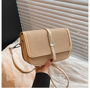 Close-up of beige crossbody bag featuring woven texture and silver metal buckle