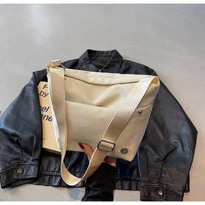 Détail du sac seau en nylon crème avec bandoulière réglable sur cuir noir