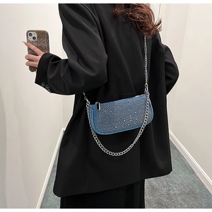 Detail of dark blue denim saddle bag with silver rhinestones and chain strap on shoulder
