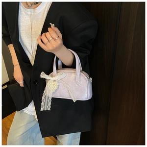Détail du sac polochon lilas brillant avec nœud en dentelle et breloque cœur perlé