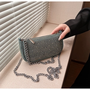 Close-up of denim saddle bag featuring silver metal studs and chunky chain strap