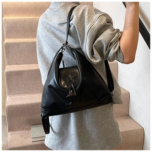 Detail shot of black faux leather shoulder bag with star charm and metallic buckle accent