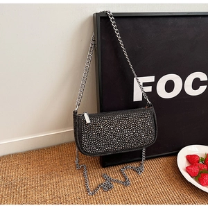 Detail of black saddle bag with silver studs, metal chain strap and top zipper closure