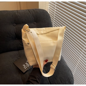 Détail du sac bandoulière en nylon crème avec sangle large et boucle en métal argenté