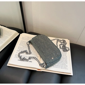 Close-up of green rhinestone evening bag with silver chain strap on open book