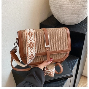 Detail of vintage crossbody bag with woven texture, leather trim and patterned strap