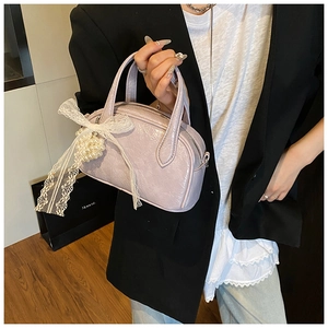 Gros plan d'un sac polochon lilas en cuir verni avec nœud en dentelle et perles
