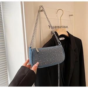 Detailed macro view of denim saddle bag with silver studs and chain shoulder strap