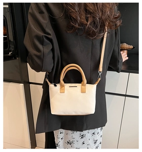 Detailed view of bucket bag with camel leather handles and adjustable shoulder strap