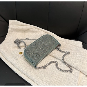 Close-up of blue denim mini bag with sparkling rhinestones and silver chain strap